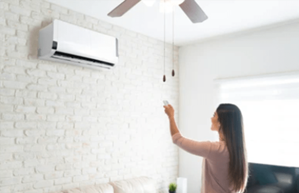 a woman is using remote control to control the indoor unit of heat pump